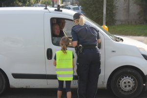 Dziecko wraz z policjantem kontrolujące samochód.