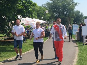 Polscy medaliści biegną w sztafecie z ogniem olimpijskim.