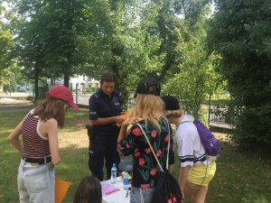 Policjantka tłumaczy dziewczynkom z jednej z drużyn na czym polega zadanie do wykonania.