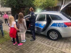Policjantka prezentuje dzieciom policyjny radiowóz