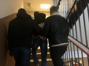 Dwóch policjantów prowadzi po schodach zatrzymanego mężczyznę