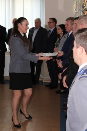 Na zdjęciu policjantka rozdaje zaproszonym gościom opłatek