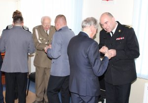 Pierwszy Zastępca Komendanta Stołecznego Policji inspektor Krzysztof Smela dzieli się opłatkiem z zaproszonymi gośćmi.