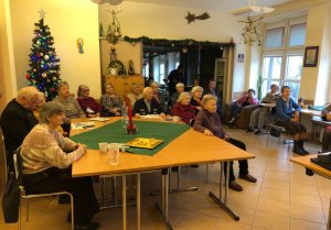 Na zdjęciu w sali Centrum Aktywizacji Seniorów na Żoliborzu przy stolikach siedzą starsze osoby, słuchają o metodach oszustw.