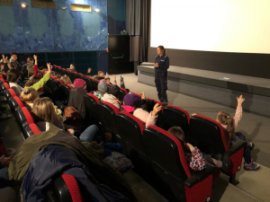 Na zdjęciu w sali kina Wisła policjantka opowiada licznie zgromadzonym dzieciom o zasadach bezpieczeństwa.