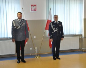 Na zdjęciu na tle flag Rzeczypospolitej Polskiej stoją w odstępach Komendant Stołeczny Policji nadinspektor Paweł Dobrodziej oraz Komendant Rejonowy Policji Warszawa V nadkomisarz Wojciech Turek