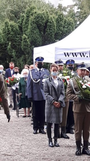 Na zdjęciu przed pomnikiem stoją osoby biorące udział w uroczystości patriotycznej.