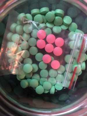 Na zdjęciu słoik i torebka z kolorowymi tabletkami.
