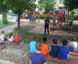 Policjantka na szkolnym boisku prowadzi pogadankę z dziećmi