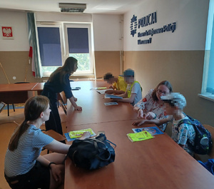 Policjanta przekazuje dzieciom elementy odblaskowe.
