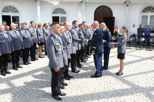 Policjant wręcza drugiemu policjantowi dokument.