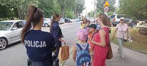 Policjantki rozmawiają z grupą dzieci na ulicy.