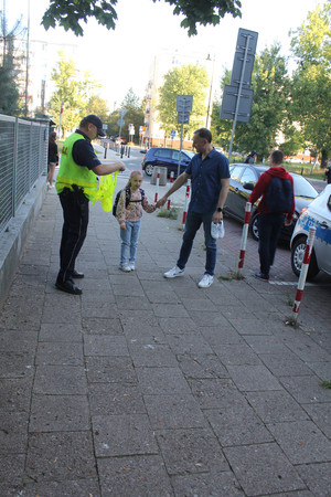 Policjant daje dziewczynce kamizelkę.