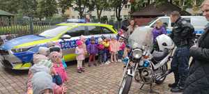 Radiowóz i policyjny motocykl. Obok stoi grupa dzieci.