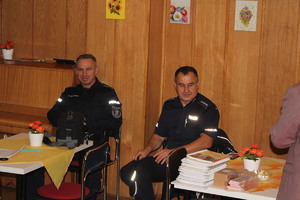 Na krzesłach siedzą dwaj policjanci.