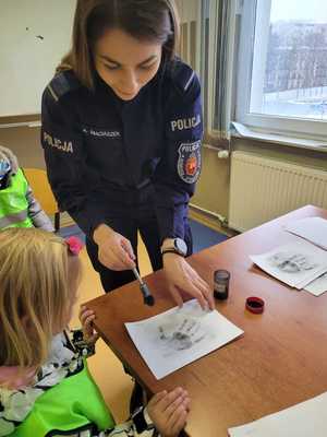 Policjantka robi odcisk dłoni.