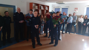 Policjanci stoją z kwiatami.