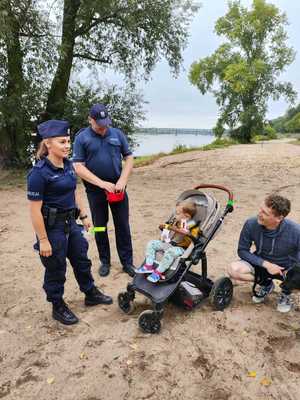 Policjanci stoją razem z dzieckiem, mężczyzną i psem.