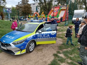 Policjanci i dzieci przy radiowozie.