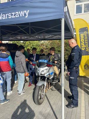 Chłopiec siedzi na motocyklu, obok stoi policjant.