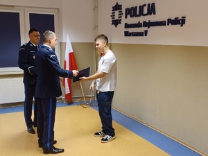 Policjant wręcza uczniowi list gratulacyjny.