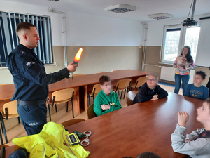 Policjant pokazuje dzieciom latarkę.