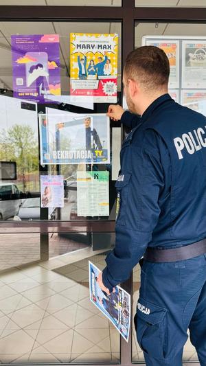 Policjant zawiesza plakat.