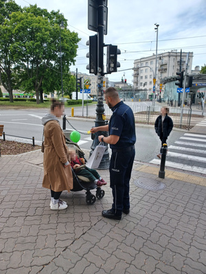 Policjant stoi z kobietą i dzieckiem w wózku.