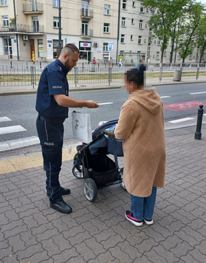 Policjant stoi z kobietą i dzieckiem w wózku.