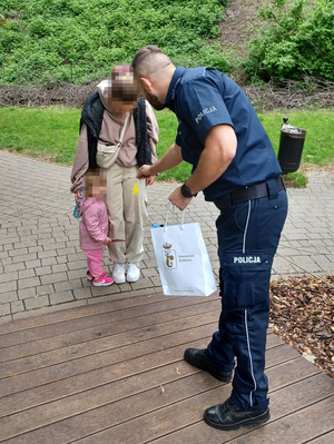 Policjant stoi z kobietą i dzieckiem.