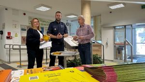 Policjant z dwoma osobami stoi przy stoliku.