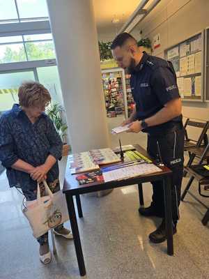 Policjant stoi przy stoisku promocyjnym.