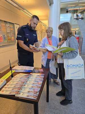 Policjant stoi przy stoisku promocyjnym.