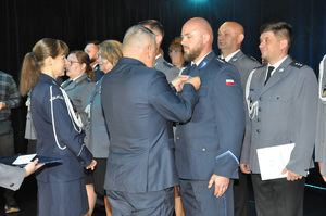 Mężczyzna przypina medal policjantowi.