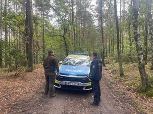 Policjant i leśniczy przy radiowozie.