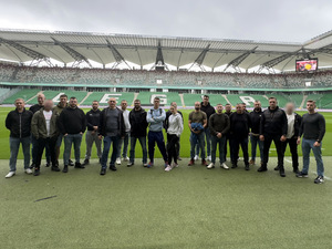 Mężczyźni  stoją na tle stadionu.