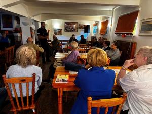Policjant stoi przed starszymi osobami.