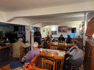 Policjant stoi przed starszymi osobami.