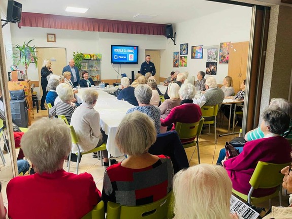 Policjant stoi przed grupą osób.