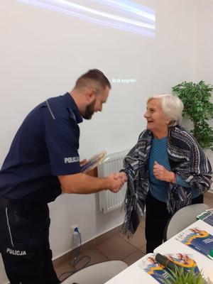 Policjant wręcza ulotkę.