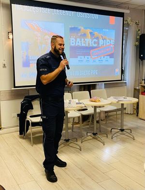 Policjant stoi z mikrofonem.