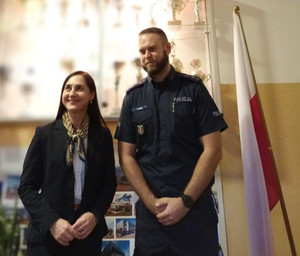 Policjant stoi obok kobiety.