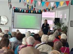 Policjantka stoi przed starszymi osobami.