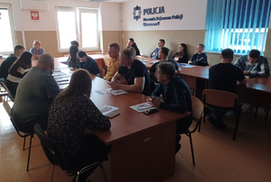 Osoby siedzą przy stołach.