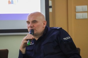 Policjant mówi do mikrofonu.