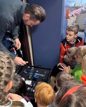 Policjant pokazuje dzieciom walizkę.