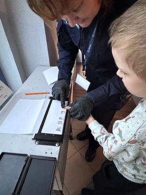 Policjant wykonuje daktyloskopię.