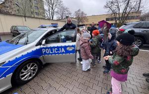 Policjant i dzieci stoją przy radiowozie.