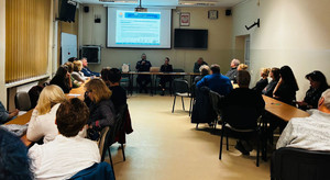 Policjant siedzi za stołem, przed uczniami.