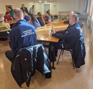 Policjanci siedzą wśród grupy osób.